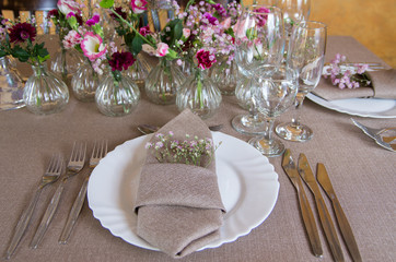 Restaurant table with cutlery and vases with flowers.