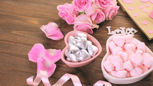 Pink roses with chocolates on rustic wood table