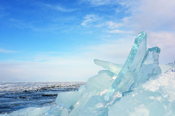 Pile of transparent blue ice blocks on the shore of a frozen winter lake Baikal in Siberia