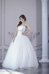 Naklejka premium Beauty bride in bridal gown indoors. Beautiful model girl in a white wedding dress. Female portrait of cute lady. Woman with hairstyle