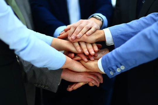 Close-up of business partners making pile of hands at meeting