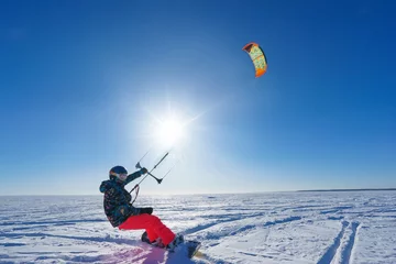 Afwasbaar Fotobehang Wintersport The sportsman on a snowboard runs kite