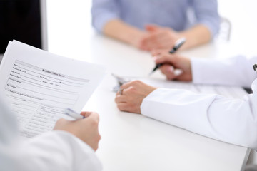 Close-up of a female doctor holding application form while consulting patient
