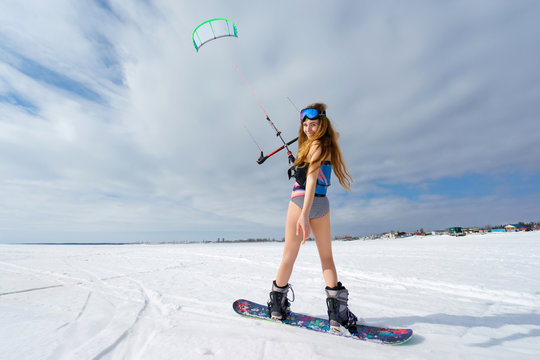 A slender girl in a bathing suit in the winter. Snowboarding and