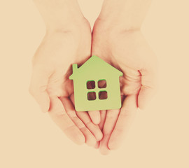 Female hands with model of house on light background