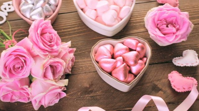 Pink roses with chocolates on rustic wood table
