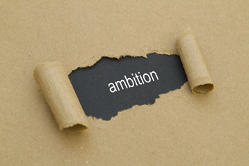 Ambition word written under torn paper.