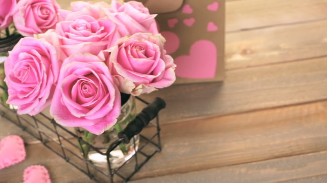 Pink roses in jars on rustic wood table
