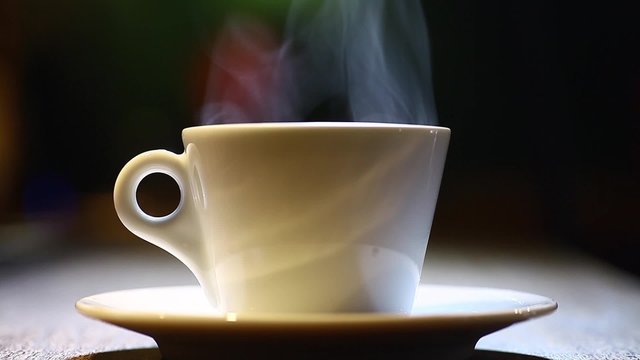 Color footage of a coffee mug put on a plate, with steam.