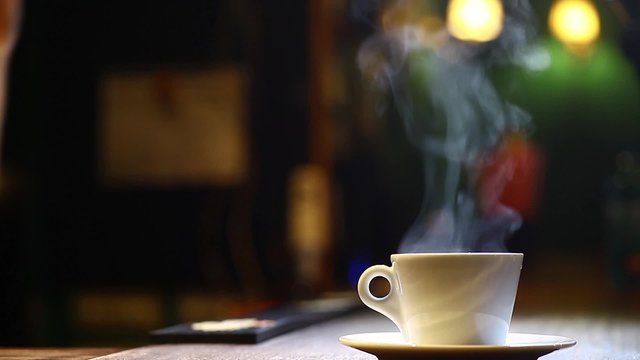 Color footage of a coffee mug put on a plate, with steam.