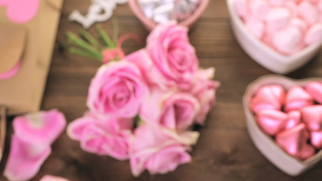 Pink roses with chocolates on rustic wood table