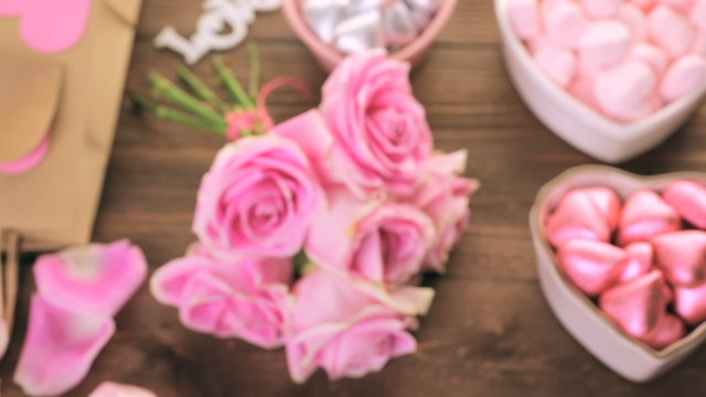 Pink roses with chocolates on rustic wood table