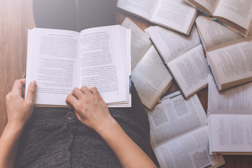 Woman reading a few books on the floor - 106321764