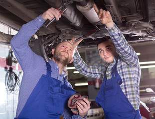Obraz na płótnie Canvas Two car mechanics at workshop
