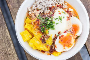 bowl of noodles with vegetables and soft boiled egg on wooden ta