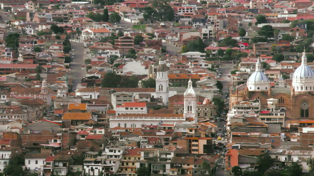 A panoramic aerial shot pans across the historic city of Cuenca, Ecuador, dense colonial architecture with terracotta rooftops and the white-domed cathedral as the focal point.