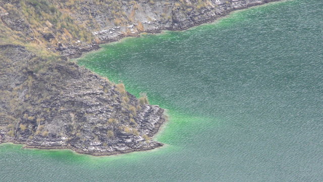 Experience the breathtaking beauty of the turquoise waters of Quilotoa Crater Lagoon through a mesmerizing high angle static shot.