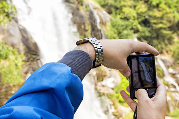 man making photo of waterfall,hands with photo camera