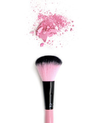 Close up of crushed blush on white background and cosmetic brush