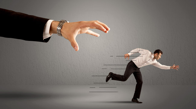 Businessman running away from a huge hand