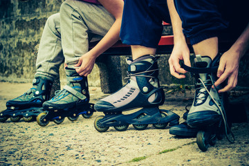 People friends putting on roller skates outdoor.