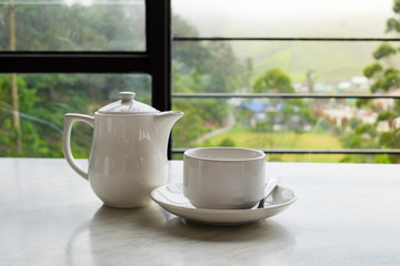 White cup of tea and teapot on white marble table