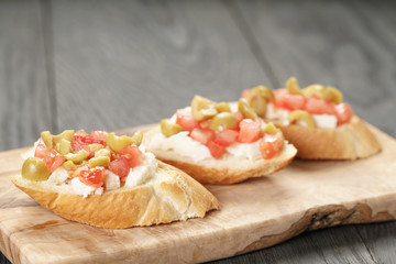 crostini with tomato, mozzarella and olives on wooden table