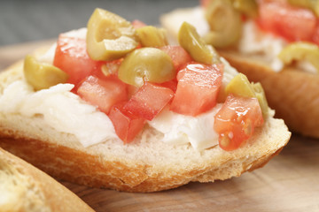 crostini with tomato, mozzarella and olives on wooden table
