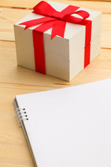 Blank paper with box gift on wooden table use for background