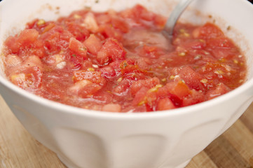 White bowl with tomato, oil, garlic, oregano, salt and pepper