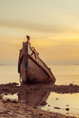 Young woman is sitting on the shipwreck.