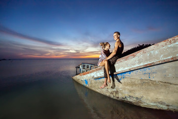 Young laughing couple is sitting on the sunken ship