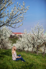 girl with camera is sitting in the garden of blooming apple trees