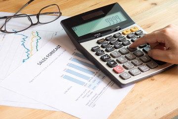 Businessman examining financial sale forecast charts using a calculator