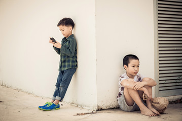 Young boy play smartphone compare with poor boy