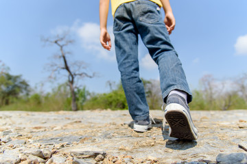 Boy walking on the rocky land.