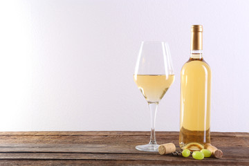Wine and grape on wooden table against light background