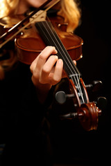 Musician plays violin on black background, close up