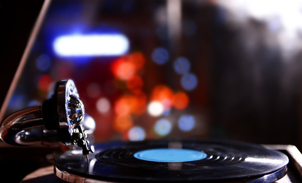 Turntable with vinyl record on dark blurred background