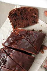 Chocolate sliced cake with icing on tablecloth