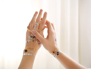 Silver, golden flash tattoo and bracelets on female hands over white background