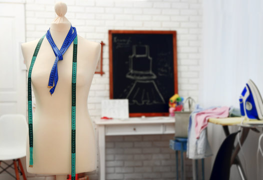 Tailor dummy with measuring tapes in fashion studio