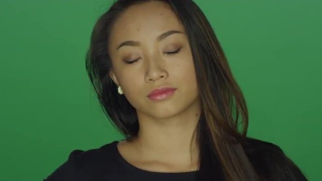 Beautiful young woman looking sad, on a green screen studio background