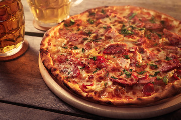 Delicious pizza  and glasses of beer are on wooden table, close up