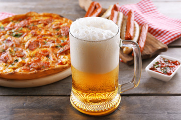 Grilled sausages, delicious pizza and glass of beer on wooden table, close up