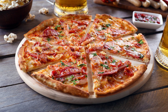 Sliced pizza and glass of beer on wooden table, close up