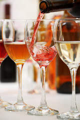 Red wine pouring into glasses, closeup