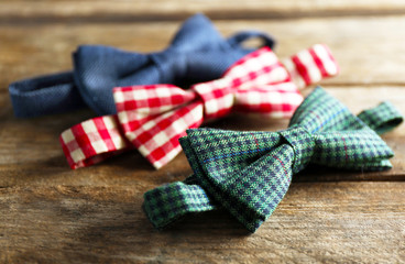 Different bow ties on wooden background
