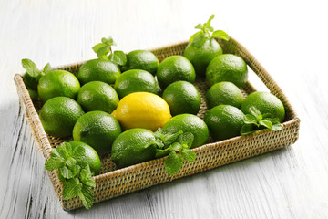 Wicker basket of limes and one lemon on table