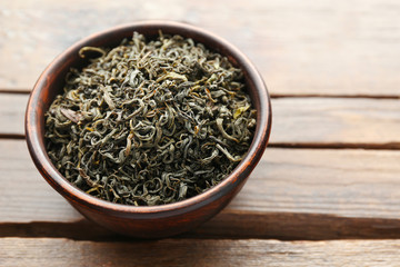Green tea in a round bowl on wooden table, close up